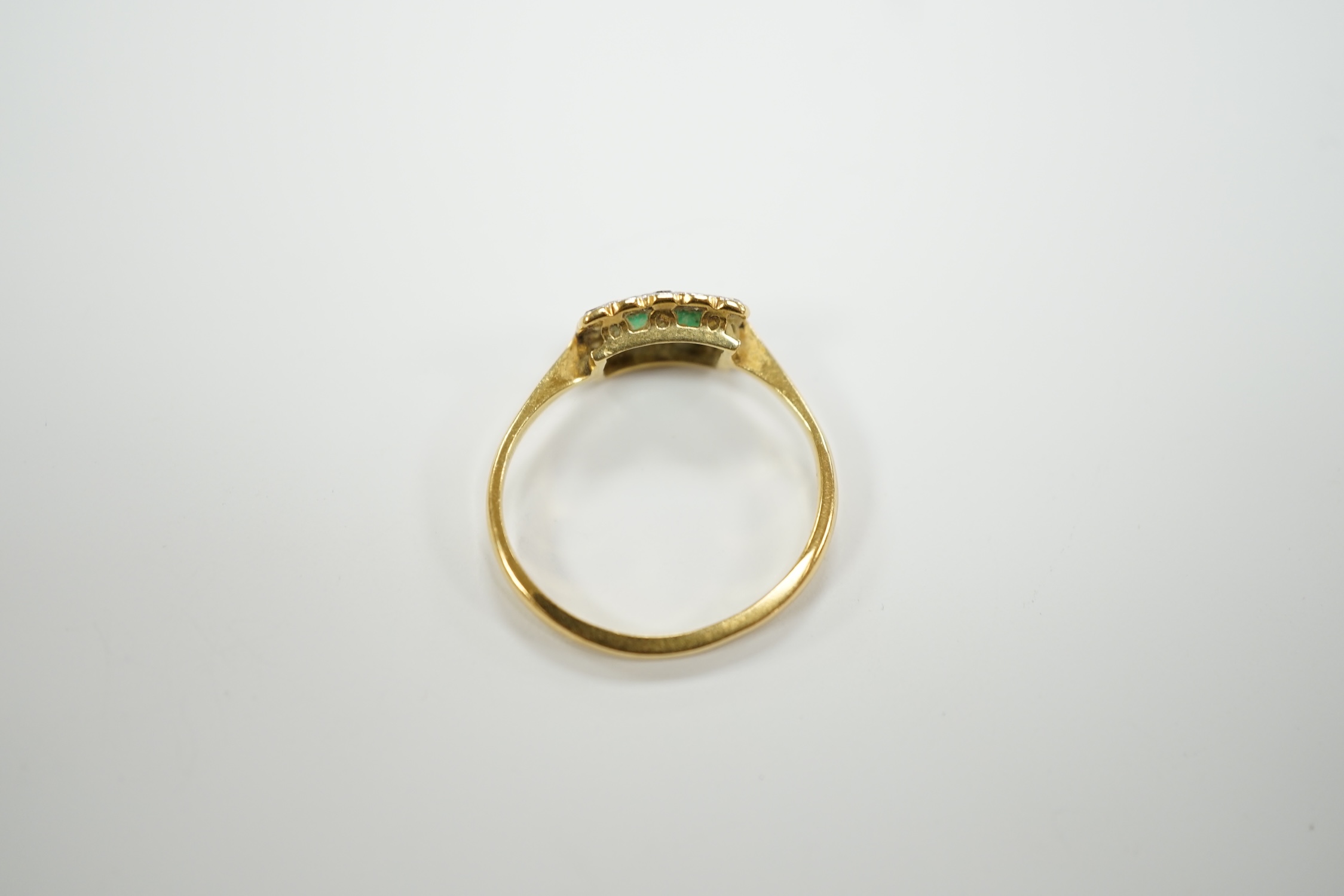 An 18ct, two stone emerald and diamond cluster set tablet ring, size M/N, gross weight 2.2 grams.